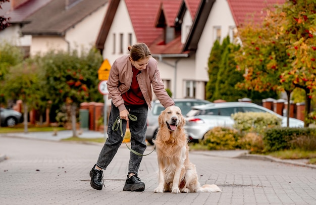 Preadolescente con chaqueta rosa con perro golden retriever sonriendo en la calle Niño bonito con perro de mascota labrador pasando tiempo al aire libre