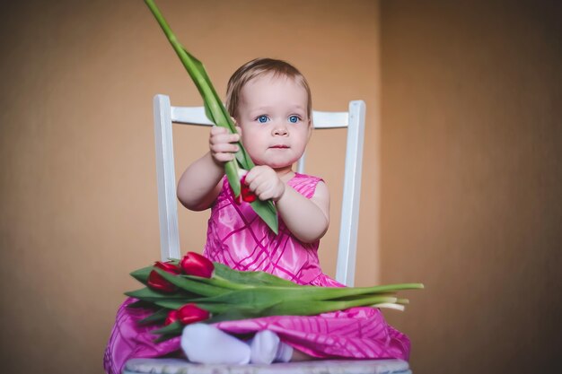 Preciosa niña con un vestido rosa con flores de tulipán.