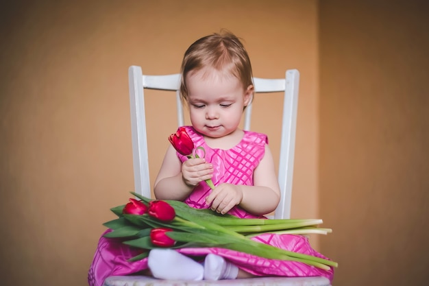 Preciosa niña con un vestido rosa con flores de tulipán.