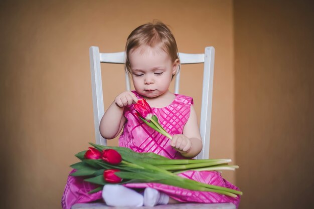 Preciosa niña con un vestido rosa con flores de tulipán.