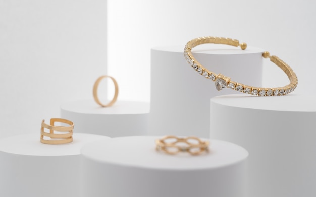 Foto preciosa pulsera preciosa con colección de diamantes y anillos en plataformas blancas.