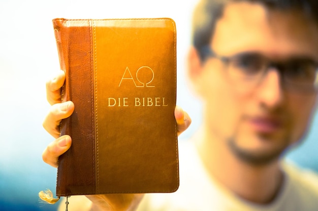 Foto predicador cristiano joven sostiene la biblia rezando