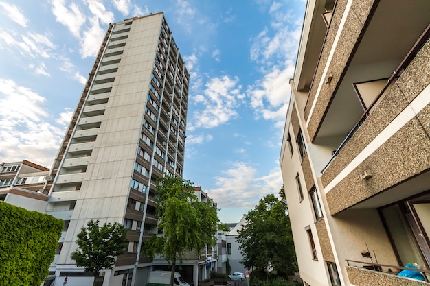 Prédio de apartamentos multistoried alto com as árvores contra o céu azul.