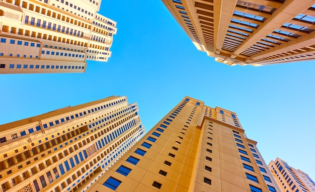 Prédios de apartamentos de vários andares contra o céu azul, Dubai, Emirados Árabes Unidos. Olhando pra cima