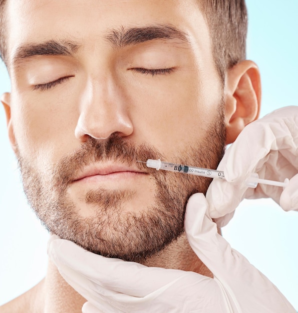 Preenchimento labial de homem e mesoterapia com mãos faciais e injeção de seringa de agulha e beleza em fundo azul Cuidados cosméticos e procedimentos dermatológicos saúde e cuidados com a pele com bem-estar e colágeno