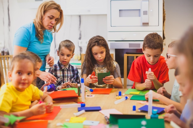 Los preescolares hacen un aplique bajo la supervisión de un educador