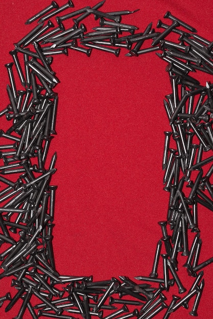 Pregos de aço preto sobre fundo vermelho bagunçado, deixando espaço no centro para texto publicitário