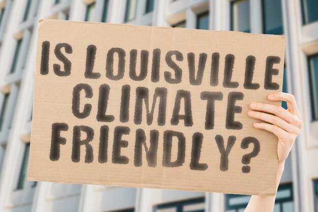 La pregunta ¿Es Louisville amigable con el clima? está en una pancarta en las manos de los hombres con un fondo borroso Equipo de apoyo Activista Atardecer urbano Carbono Ecología Energía Nuevo Calentamiento limpio Residuos