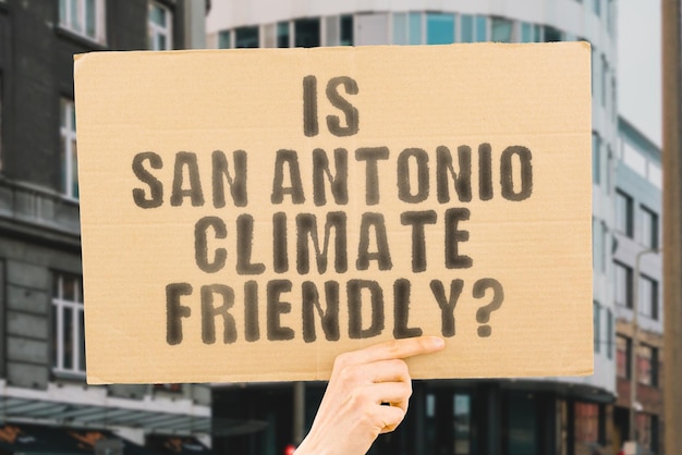 La pregunta ¿Es San Antonio amigable con el clima? está en una pancarta en las manos de los hombres con un fondo borroso Equipo de apoyo Activista Atardecer urbano Carbono Ecología Energía Nuevo Calentamiento limpio Residuos