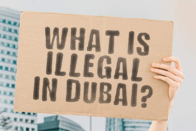 La pregunta "¿Qué es ilegal en Dubai?" en una pancarta en la mano de los hombres con un fondo borroso. Restricción. Prohibición. Reglas. Ley. Ilegal. Arábica. Prohibido. No permitido