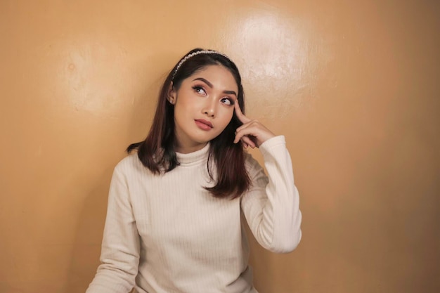 Preguntándose la cara de una joven asiática con una camisa blanca Concepto de publicidad