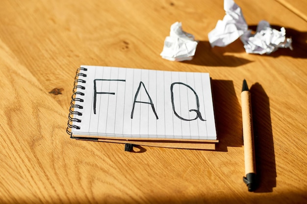 Preguntas frecuentes Preguntas frecuentes texto en el cuaderno xAon fondo de madera Concepto de comunicación empresarial social en línea