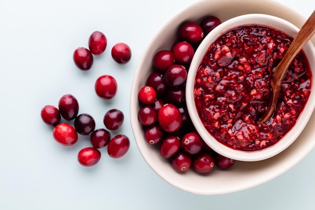 Preiselbeeren in weißer Schüssel auf pastellfarbenem Hintergrund