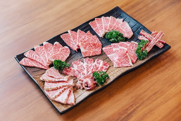 Premium Rare Slices muchas partes de carne de res Wagyu con alta textura de mármol en un plato de piedra servido para Yakiniku, carne a la parrilla