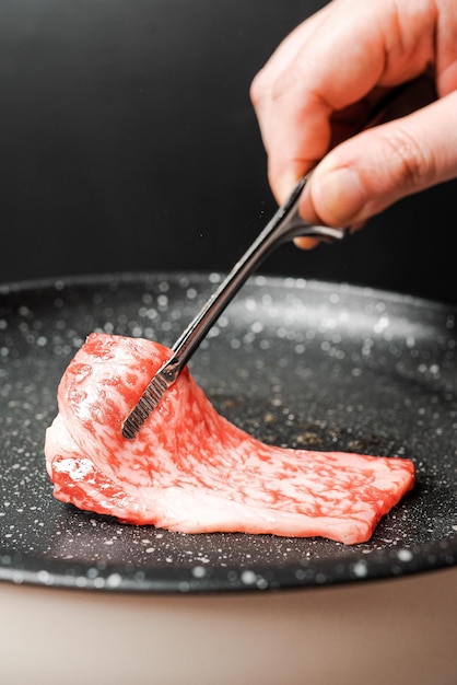 Premium Rare Slices Sirloin Wagyu A5-Rindfleisch mit stark marmorierter Textur herausnehmen und auf einer Marmorpfanne grillen