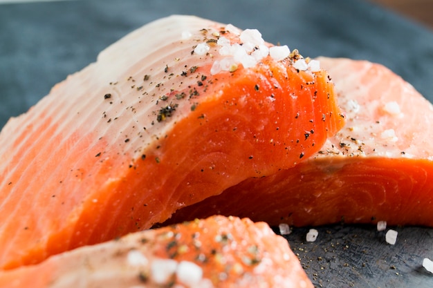 Prendedero e ingredientes de color salmón crudos para cocinar en un fondo oscuro en un estilo rústico.