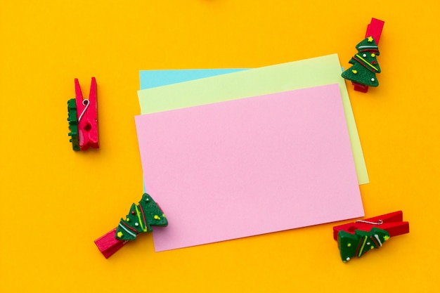 Prendedor de papel festivo de Natal vista superior e folhas de papel vazias com espaço livre para texto em um fundo amarelo vibrante