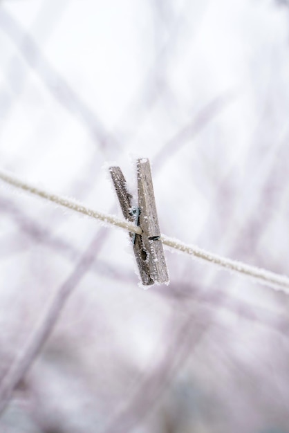 Prendedor de roupa de madeira solitário em um varal coberto de geada e neve no inverno