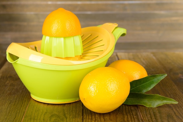 Prensa de citrinos e limões na mesa sobre fundo de madeira