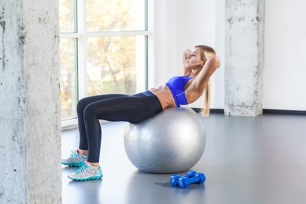 Prensa de swing de mujer rubia en la bola en forma. Tiro del estudio