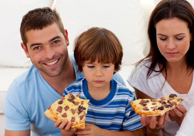 Prents y niño comiendo pizza en la sala de estar