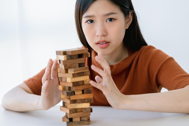 Preocupación estrés mujer inteligente asiática tratar de construir y proteger el concepto de ideas de estrategia de gestión de riesgo de torre de pila de madera