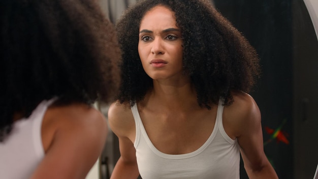 Preocupada jovem bela mulher afro-americana triste garota étnica olhando no espelho estressado sobre