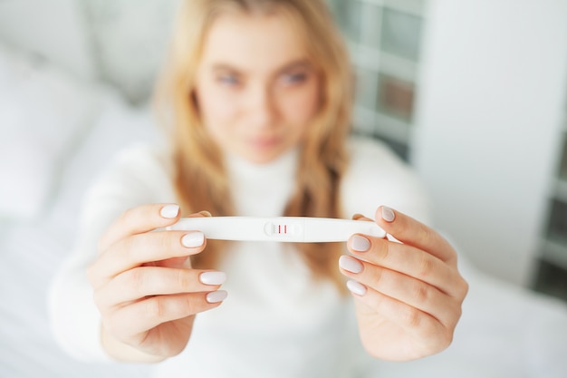 Foto preocupado mulher triste olhando para um teste de gravidez após o resultado