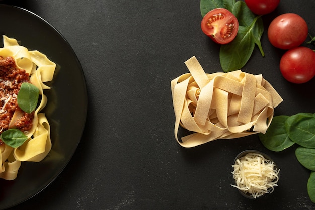 Se prepara pasta pappardelle cruda sobre un fondo oscuro con ingredientes para cocinar pasta pappardelle