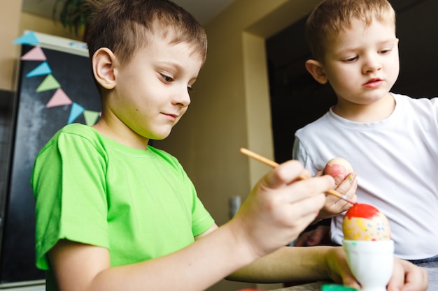 Preparação da Páscoa para duas crianças pintando ovos de Páscoa e decorações festivas em casa