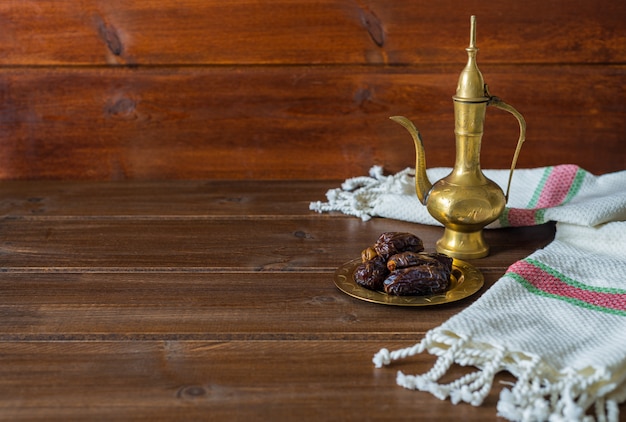 Foto preparação de alimentos do ramadã, bule de chá com datas, comida iftar em fundo de madeira com espaço de cópia