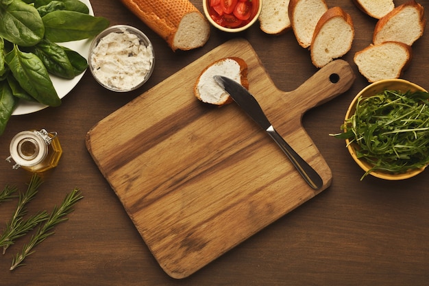 Preparação de alimentos saudáveis. Vista superior em uma tábua de madeira, pão de centeio integral, corte de tomate orgânico, cobertura de pepino e bruschetta, copie o espaço