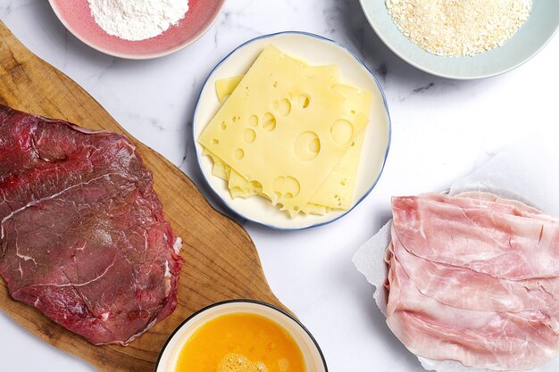 Preparação de escalope de vitela milanesa tradicional caseiro com farinha, ovo, pão ralado, queijo e fiambre