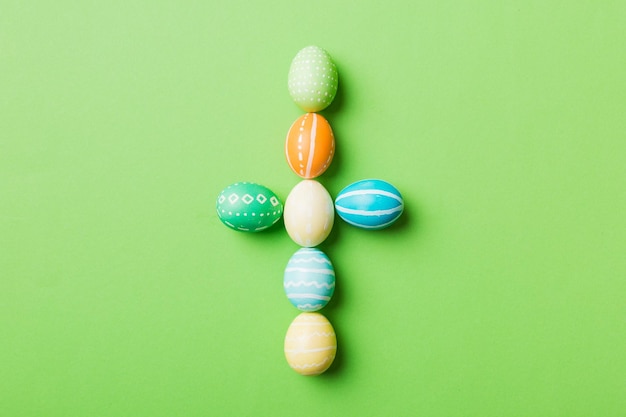 Preparação de férias Ovos de páscoa de várias cores na cruz de fundo colorido mostram o lado religioso e secular da páscoa conceito de férias de ovos de páscoa de cor pastel com espaço de cópia