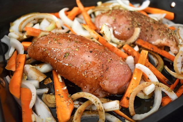 Preparação de frango assado com mel com peito de frango cru e legumes em tabuleiro de forno