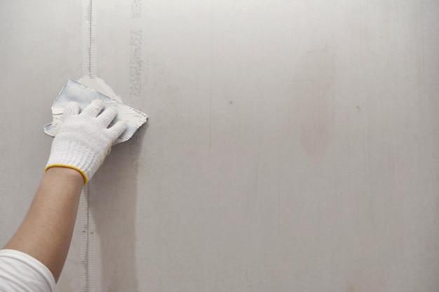 Preparação de gesso e pintura de parede fecha a mão do artesão aplicando remendo de drywall de enchimento