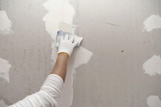 Preparação de gesso e pintura de parede fecha a mão do artesão aplicando remendo de drywall de enchimento