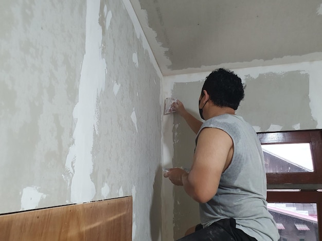 Preparação de gesso e pintura de parede Homem asiático aplicando gesso ou enchendo parede a seco