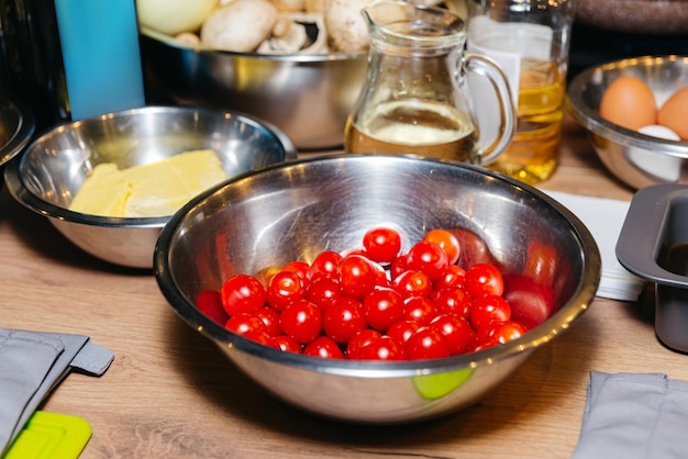 Preparação de ingredientes alimentares crus sobre a mesa tomate cereja limpo em uma tigela de metal em madeira