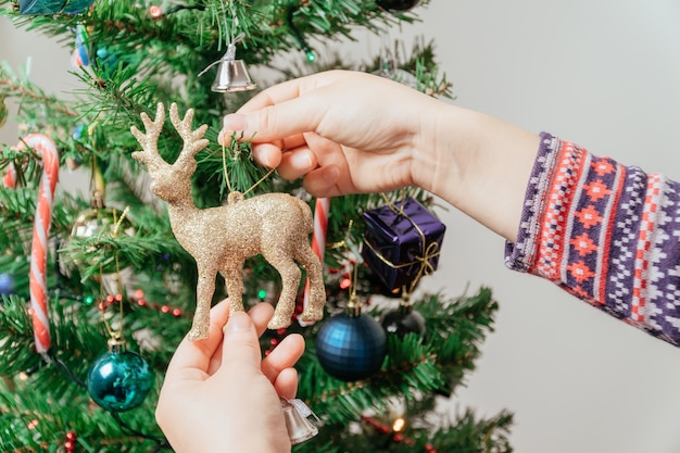 Preparação de Natal: mãos femininas decorando árvore de Natal