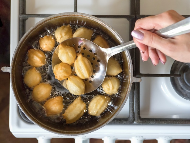 Preparação de Tulumba sobremesa árabe em óleo fervente. Tulumba - mel de esponja frito com calda árabe.