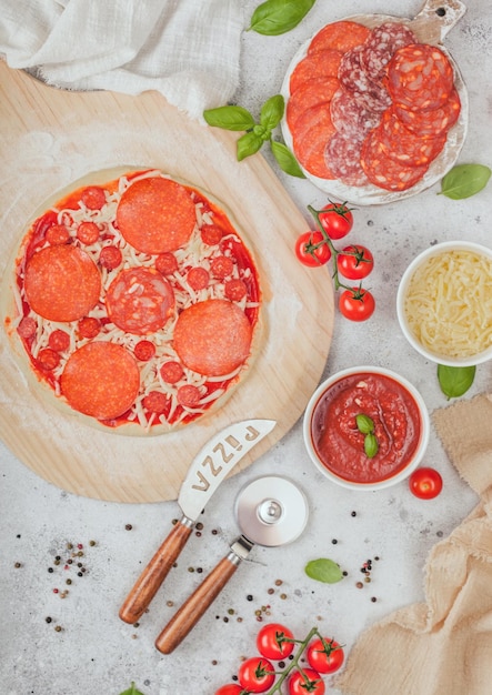 Preparação para assar pizza de pepperoni com chouriço picante de salame com cortador de roda