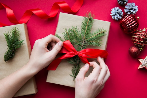 Preparação para o feriado. Ano Novo e Natal. decoração de presente. Presente de Natal nas mãos. Fundo vermelho. feriado. Ano Novo