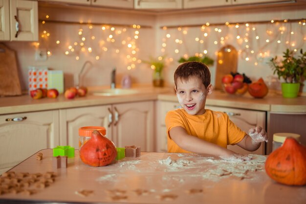 preparação para o feriado de halloween. menino alegre e feliz cozinhando biscoitos na cozinha