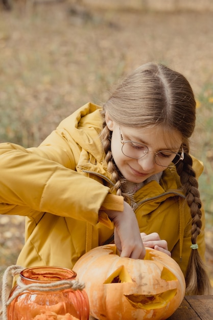 Preparação para o halloween: a menina extrai sementes de abóbora. fechar-se. conceito de decoração de férias. mulher prepara jack-o-lantern. festa de decoração. ajudante pequeno.