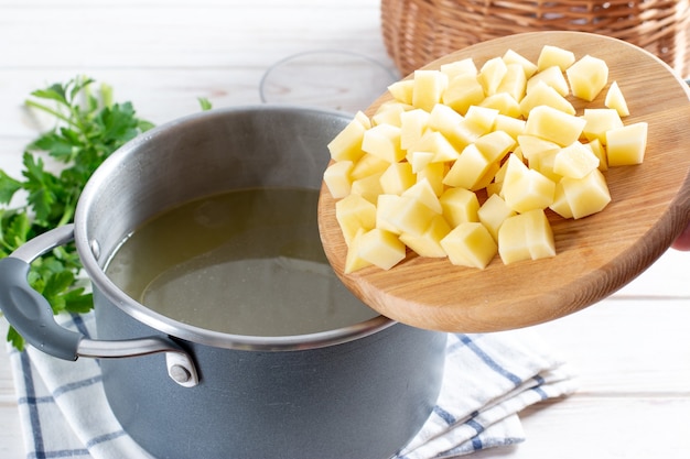 Preparação passo a passo da sopa com abóbora e vegetais, passo - adicionar batatas picadas ao caldo