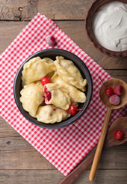 Foto preparación de albóndigas con cereza. haciendo pierogi o pyrohy, varenyky, vareniki. cocina tradicional rusa, el varenik tradicional ucraniano hecho a mano con cereza dentro