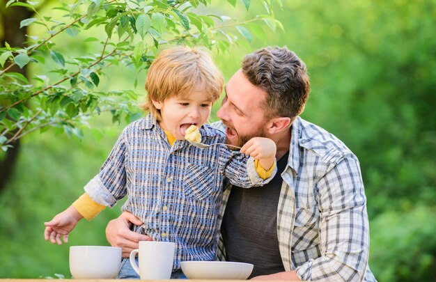 Preparación de alimentos alimentos saludables y dietas Familia feliz juntos feliz día del padre Niño pequeño con papá hijo y padre comiendo leche papilla felicidad infantil Hábitos alimentarios concepto de amor