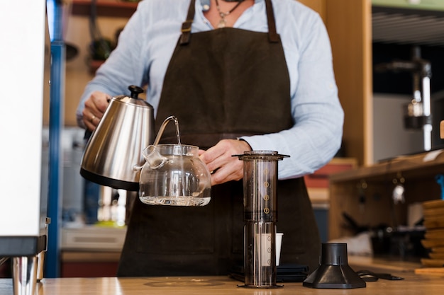 Preparación alternativa de café Aeropress por barista en la cafetería