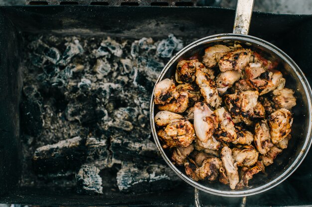 Preparación en barbacoa. Plato con carne asada en el fondo abstracto. Comida sabrosa caliente ahumada de la barbacoa en los carbones y leña quemada. Cocinar al fuego al aire libre. Buena comida con olor. Trozos de pollo frito